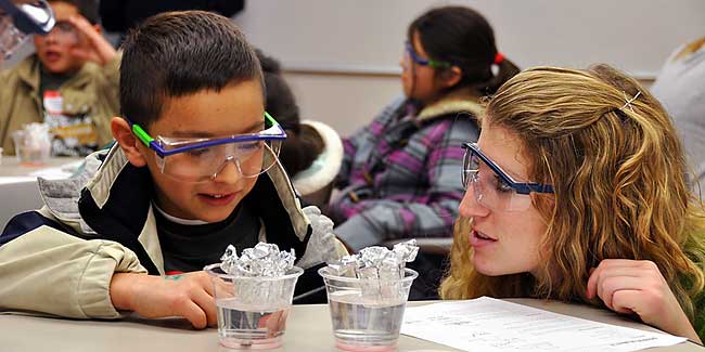 Student demonstrating science experiments with elementary students